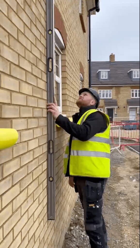 A surveyor holding a spirit level against wall